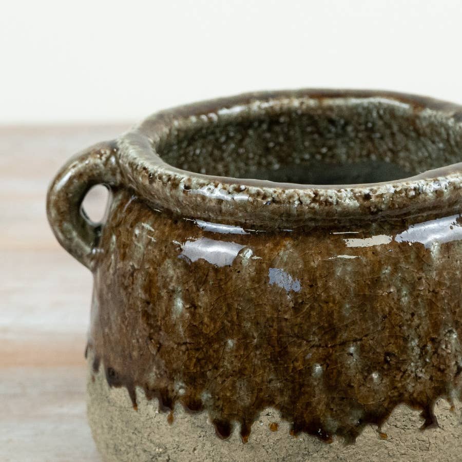 Close-up of the Agnes stoneware pot showing a glossy dark brown drip glaze over a speckled beige clay base.
