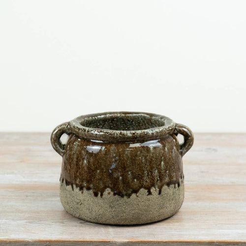 Agnes stoneware pot with twin side handles, featuring a rustic brown and green drip glaze on a wooden surface.