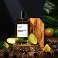 Bergamot Ember perfume bottle on a wooden stand with fruits and leaves in the background