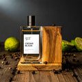 Perfume bottle labeled 'Cedar Blaze' on a wooden stand with green fruits and spices in the background.