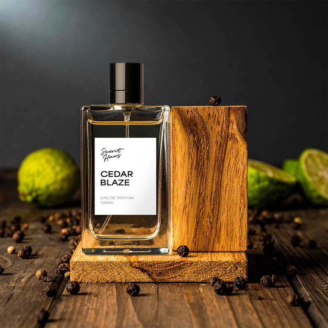 Perfume bottle labeled 'Cedar Blaze' on a wooden stand with green fruits and spices in the background.