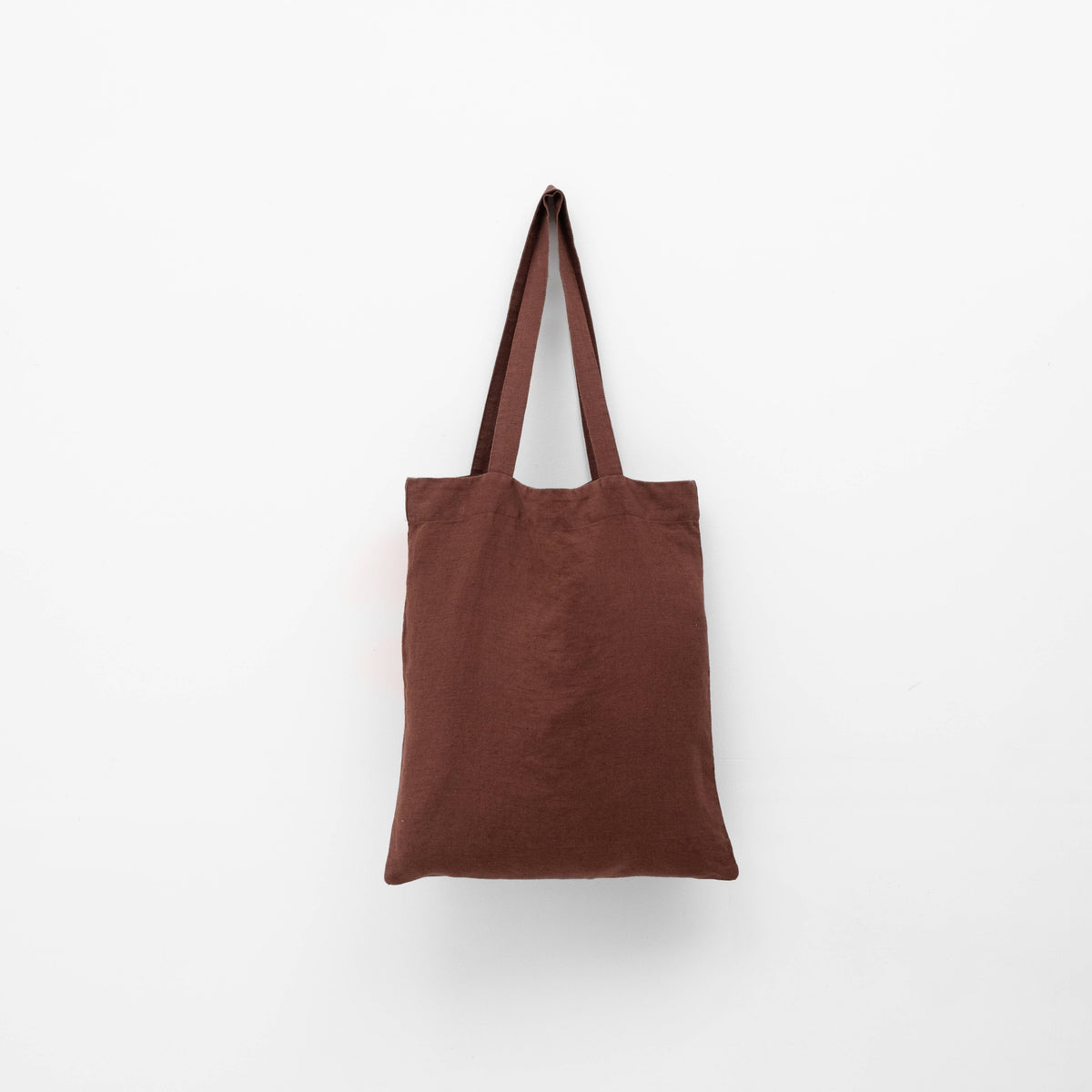 A dark brown linen tote bag with matching shoulder straps hanging against a plain white background.