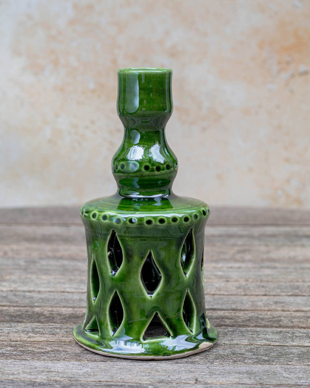 Green ceramic candle holder on a wooden surface with a beige background