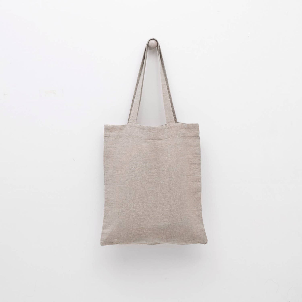 A natural linen tote bag with matching shoulder straps displayed against a plain white background.
