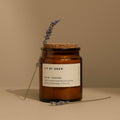 Neroli and lavender essential oil candle in amber glass with cork lid styled with dried flowers.