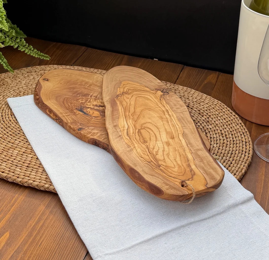 Two live-edge olive wood serving platters showing natural grain patterns on a woven placemat.