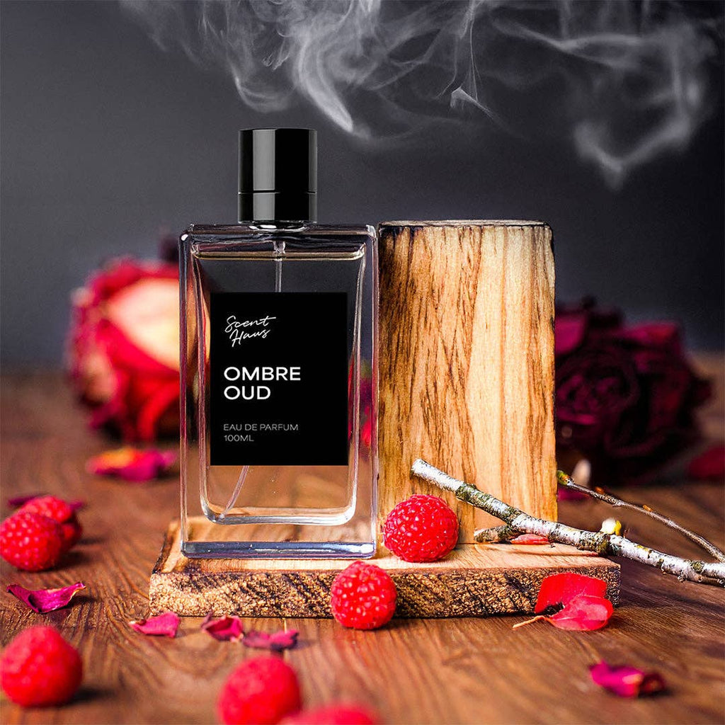 Ombre Oud perfume bottle on a wooden stand with red berries and flowers on a dark background