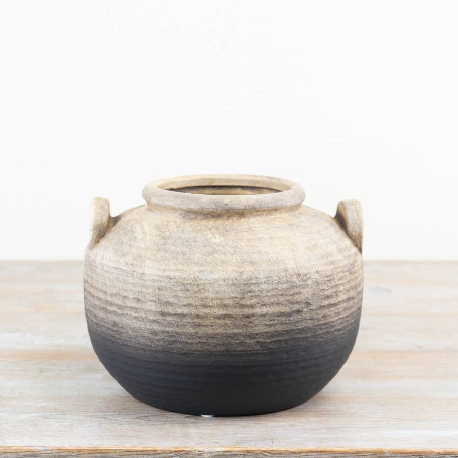 Oti rustic terracotta vase with handles in a natural and black ombre finish displayed on a wooden surface.