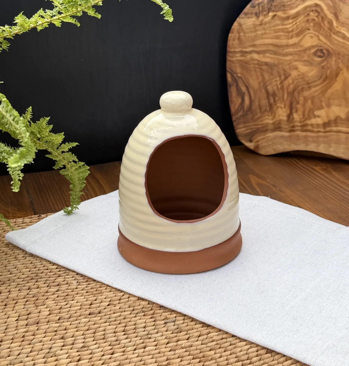 Porto terracotta salt pig with a ribbed cream glazed exterior and raw terracotta interior on a white cloth.