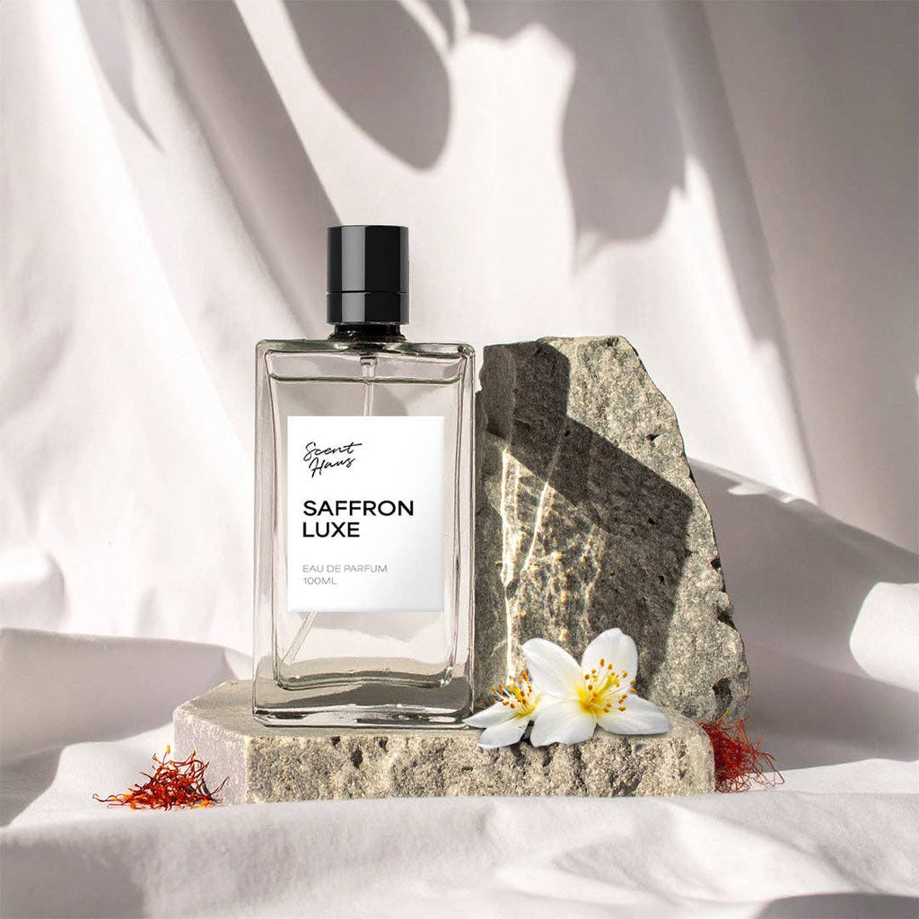 Saffron Luxe perfume bottle on a stone surface with flowers and saffron strands.
