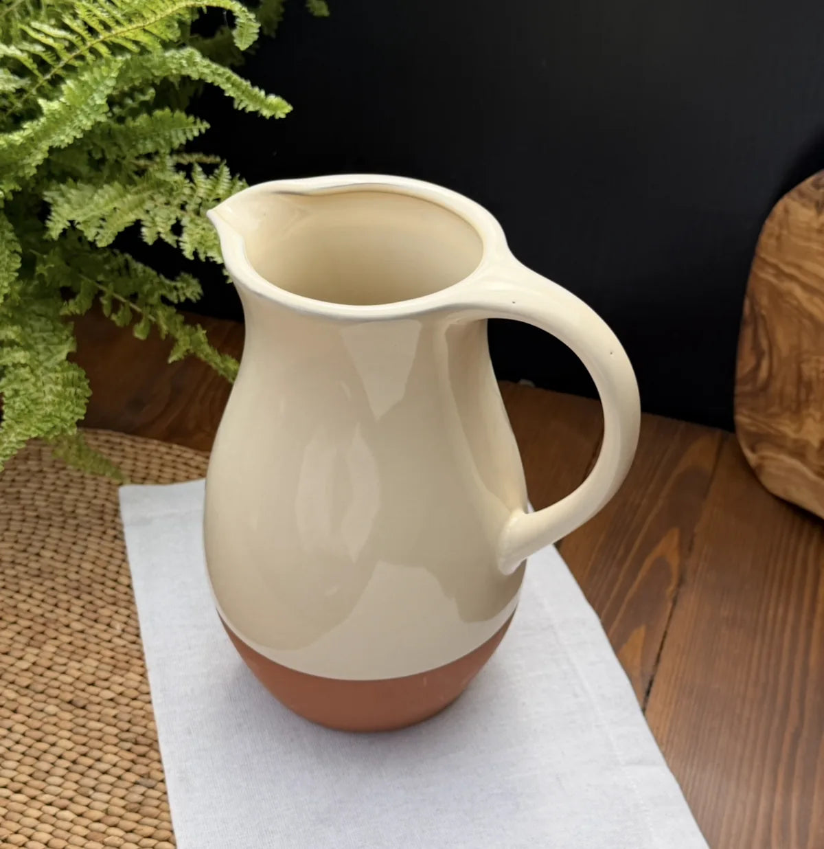 Sintra terracotta jug with a glossy cream glazed upper body and raw terracotta base on a white cloth.