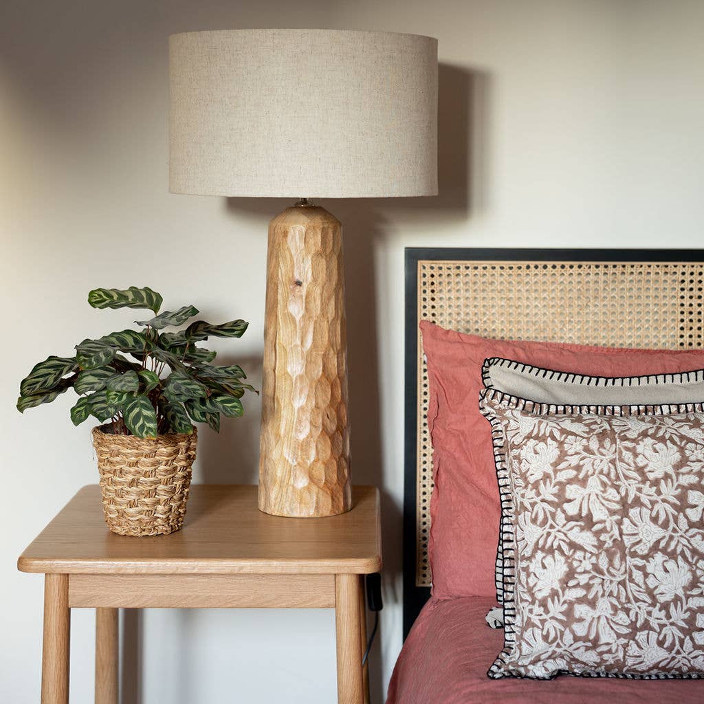 Siston wooden table lamp styled as a natural bedside lamp alongside a potted plant on a bedroom nightstand.