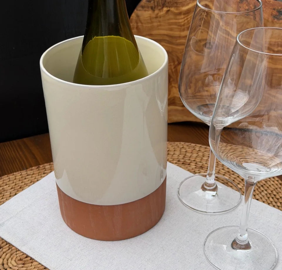Terracotta wine cooler with a cream upper glaze holding a green bottle beside two wine glasses.