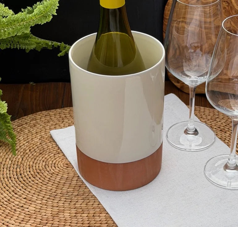 Terracotta wine cooler with glossy cream upper glaze holding a green bottle on a woven placemat.