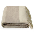 A folded Dolores woollen throw blanket with fringed edges, featuring a striped pattern in beige, taupe, and cream on a white background.