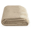 A folded Legenda throw blanket with a herringbone pattern in beige and cream, featuring cream fringe, shown on a plain white background.