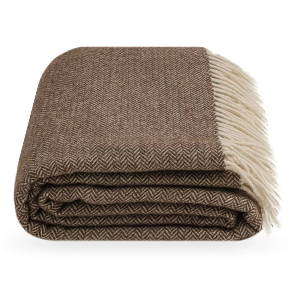 A folded brown and beige herringbone throw blanket with cream-colored fringe, shown on a clean white background.