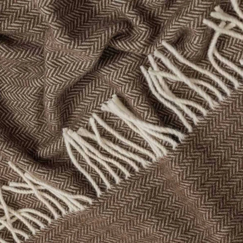 Close-up of a Legenda wool throw with a brown and beige herringbone pattern and off-white fringe.