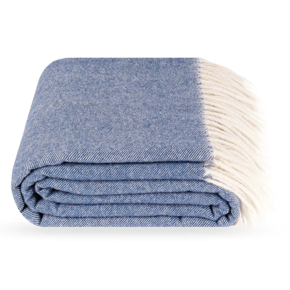 A folded blue Steppe merino wool throw blanket with cream fringe, shown on a clean white background.