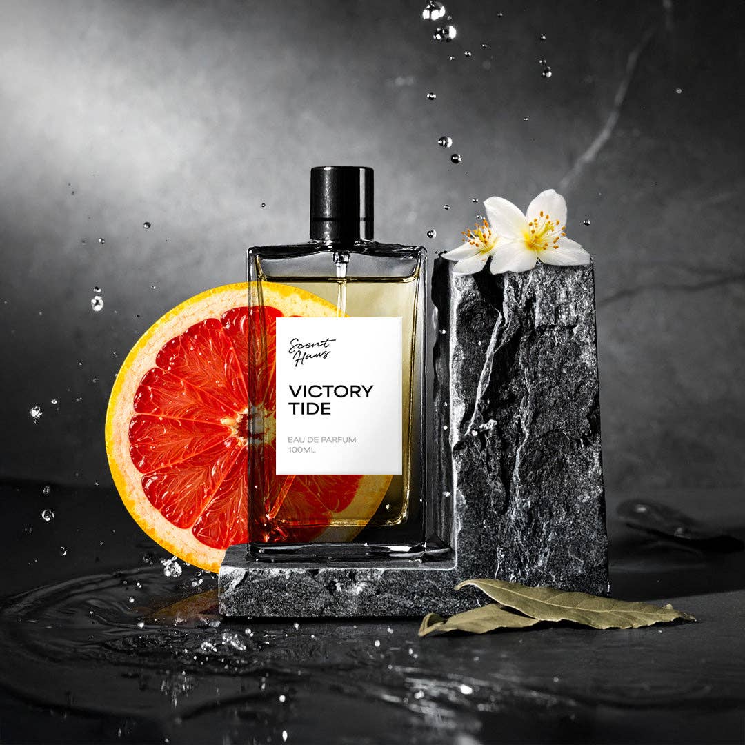 Perfume bottle labeled 'Victory Tide' with a sliced orange and flower on a dark background