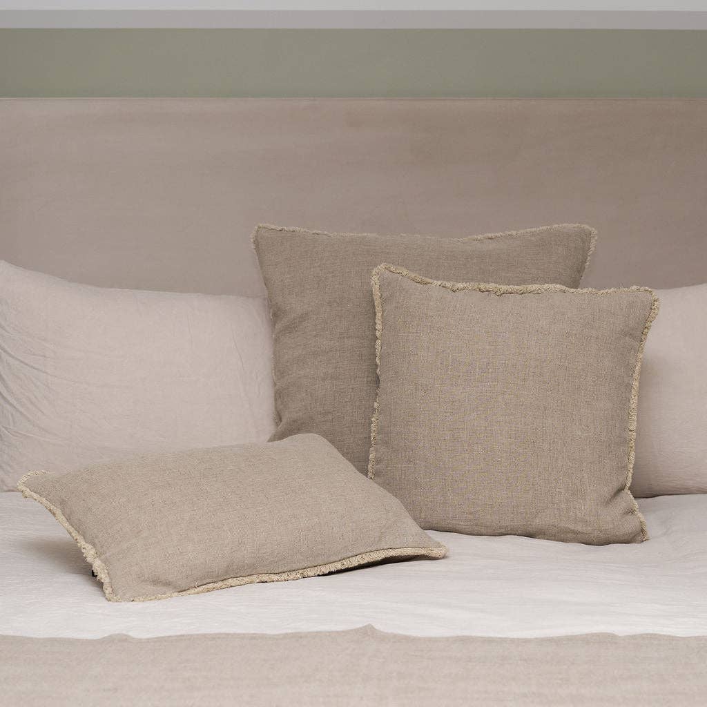 Westley Bolster linen cushions on a bed against a plain wall