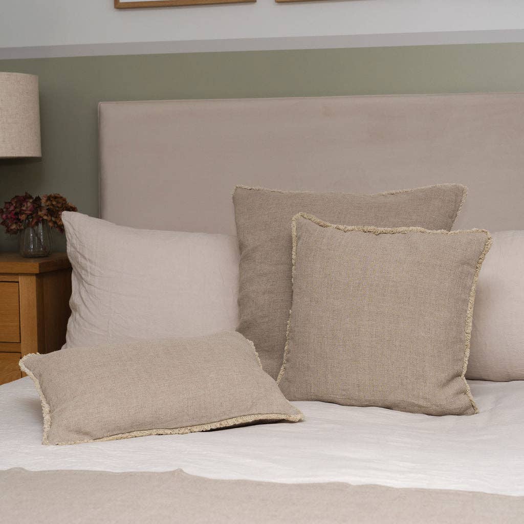 Group of three Westley linen cushion covers styled on a bed as natural material cushions.